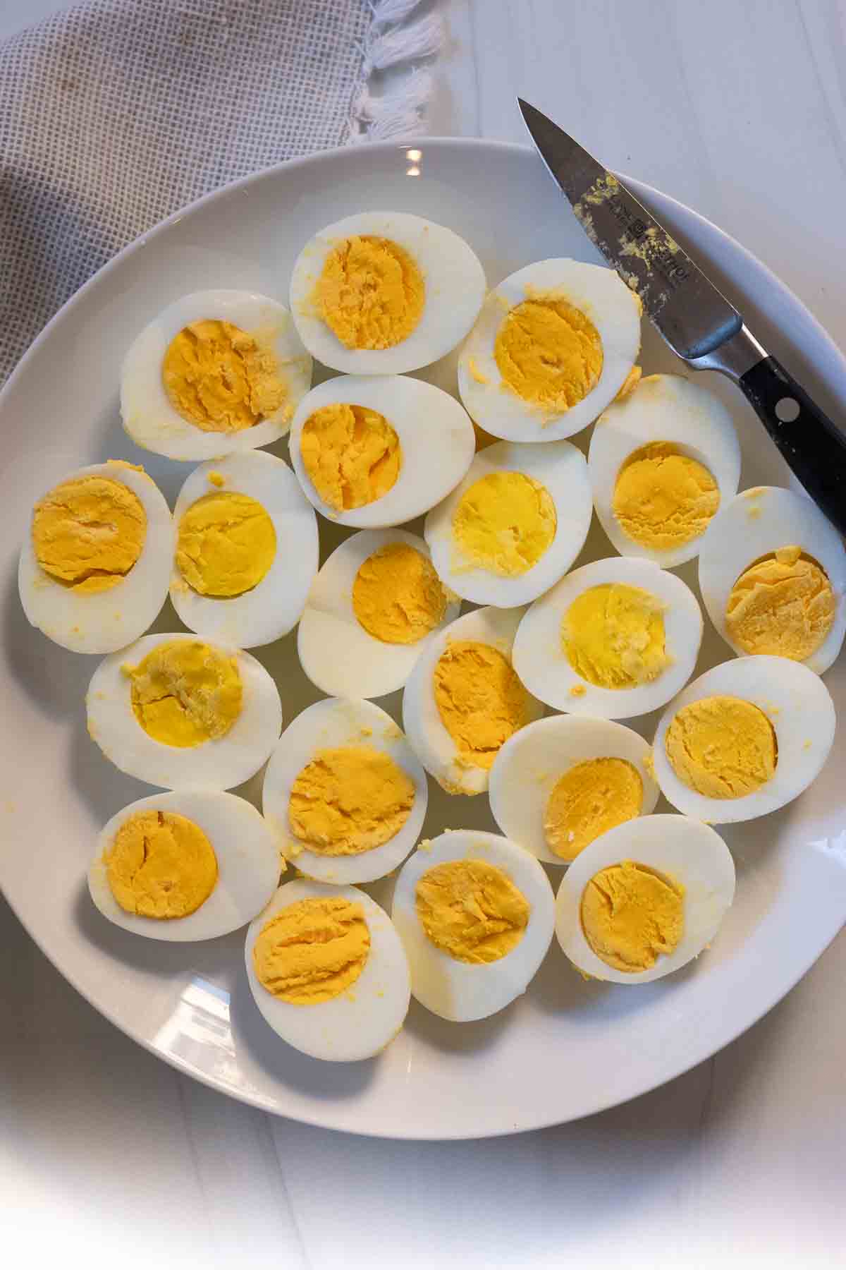 A plate of hard boiled eggs cut in half to make Bacon and Jalapeno Deviled Eggs