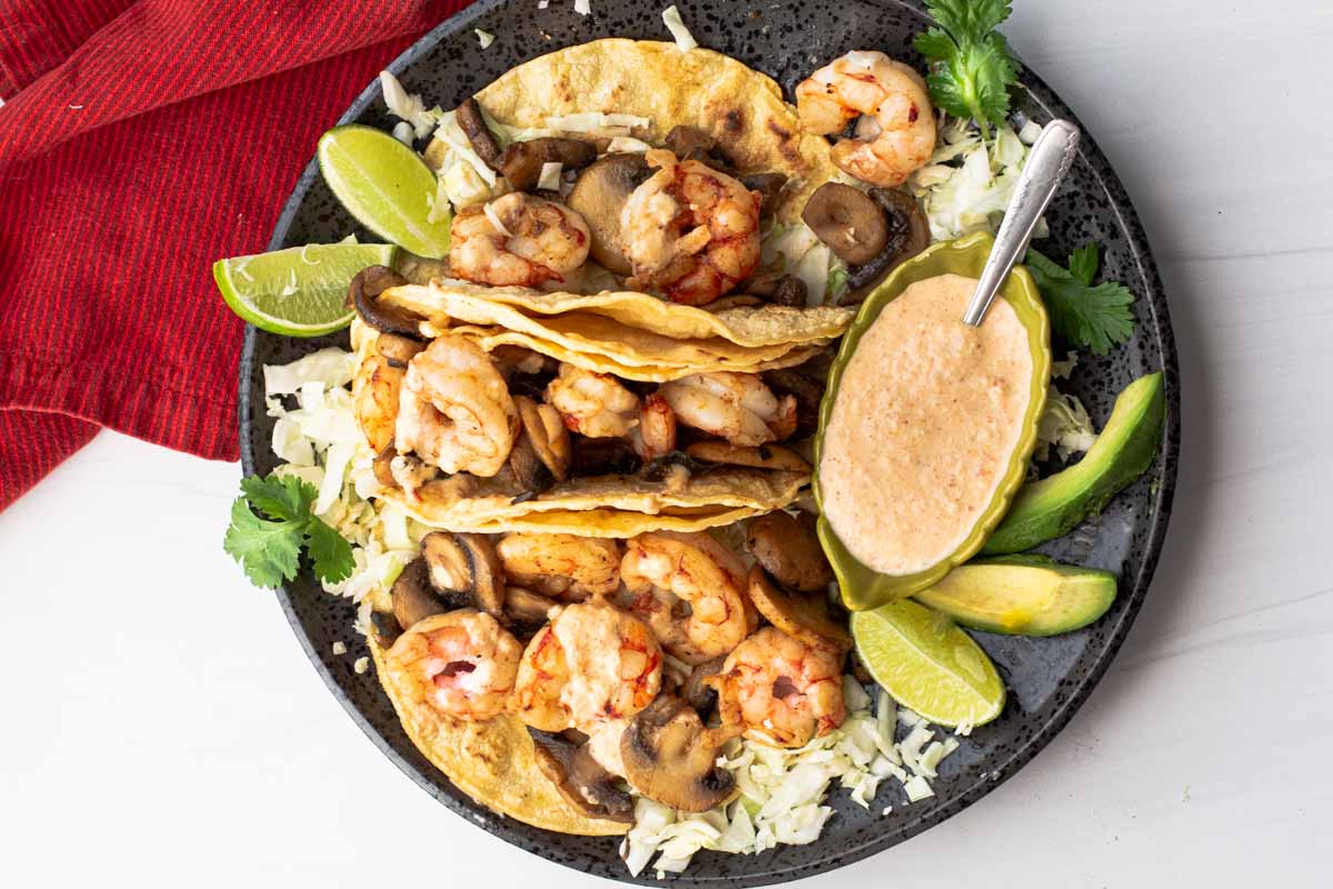 Best Shrimp Tacos Recipe served with lime wedges and sauce.