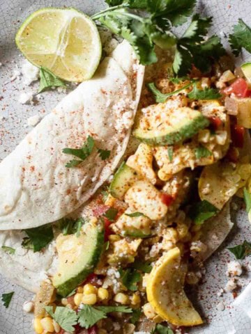 Calabacitas con queso served with a flour tortilla and a squeeze of lime.