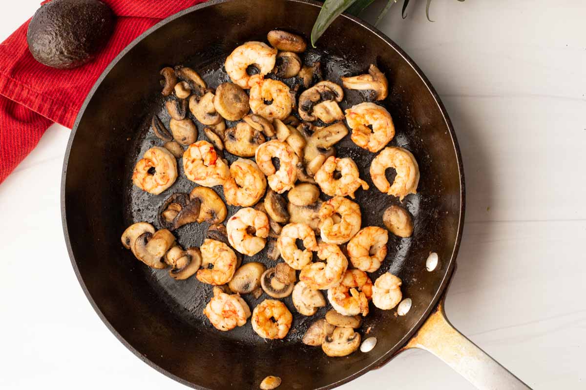 Frying shrimp and mushrooms to make simple shrimp tacos.