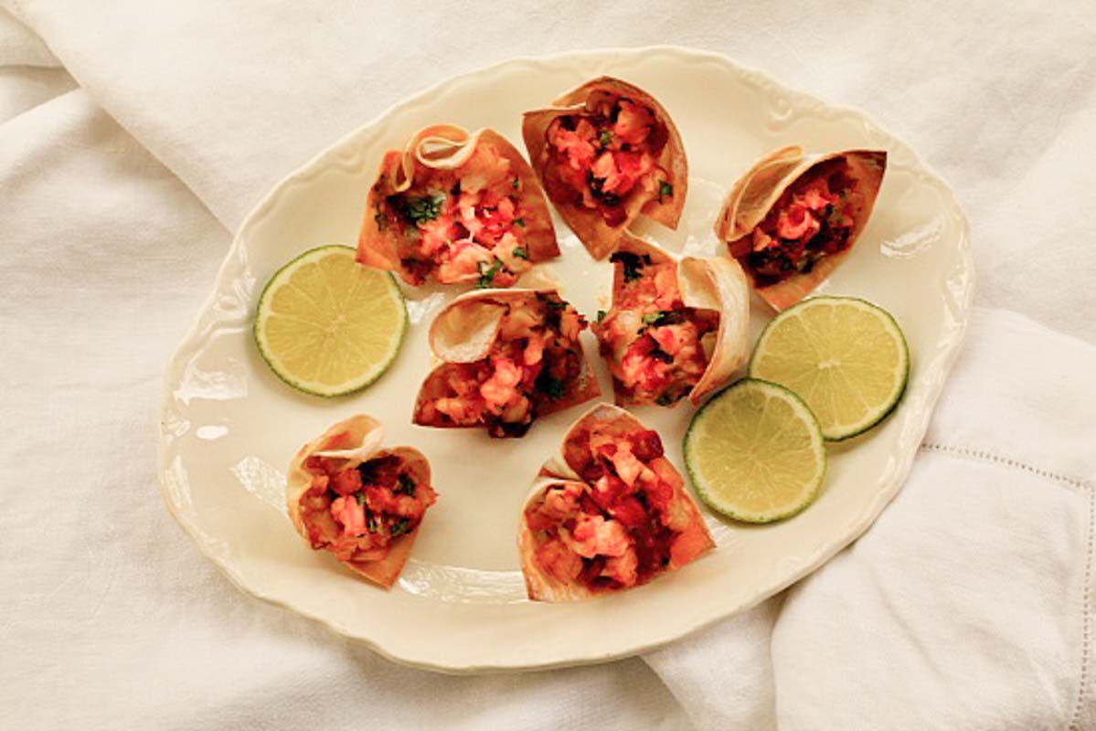 baked wonton cups filled with shrimp and served on a plate with lime slices