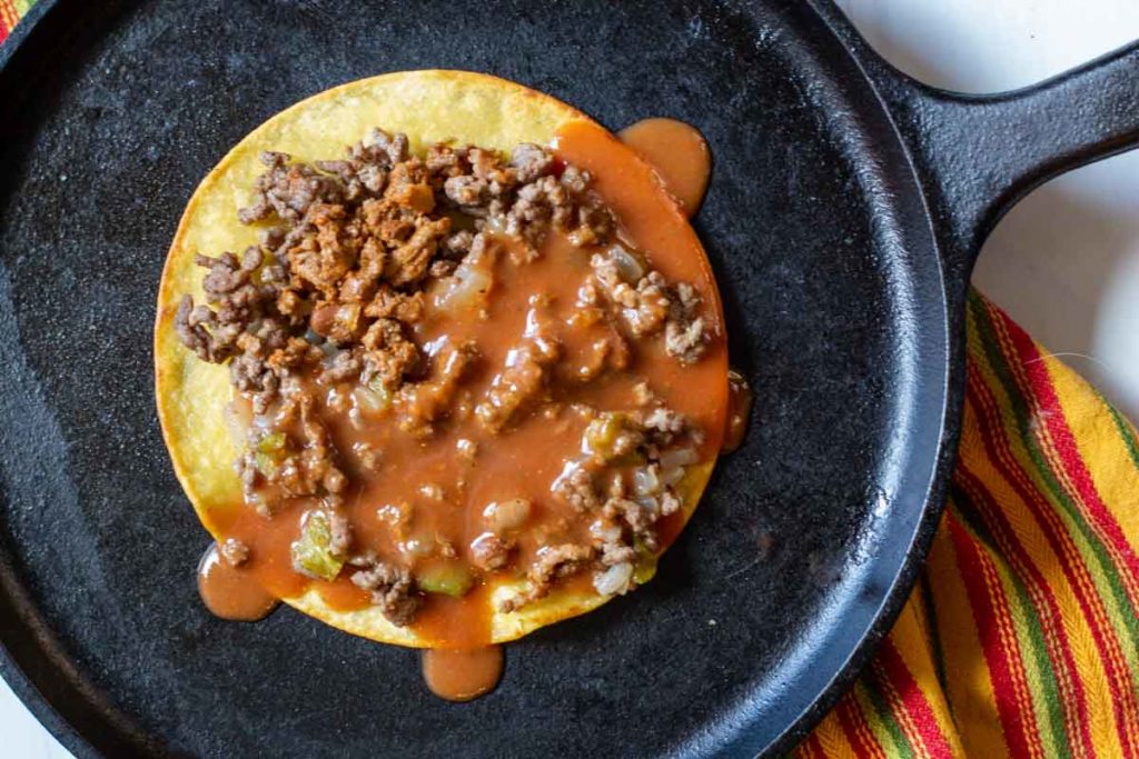 Adding enchilada sauce to tortillas for stacked enchiladas.
