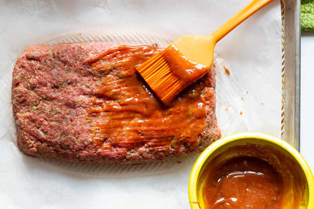 basting a meatloaf with glaze before baking