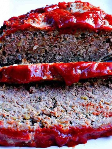 Old fashioned meatloaf on a white platter and sliced.