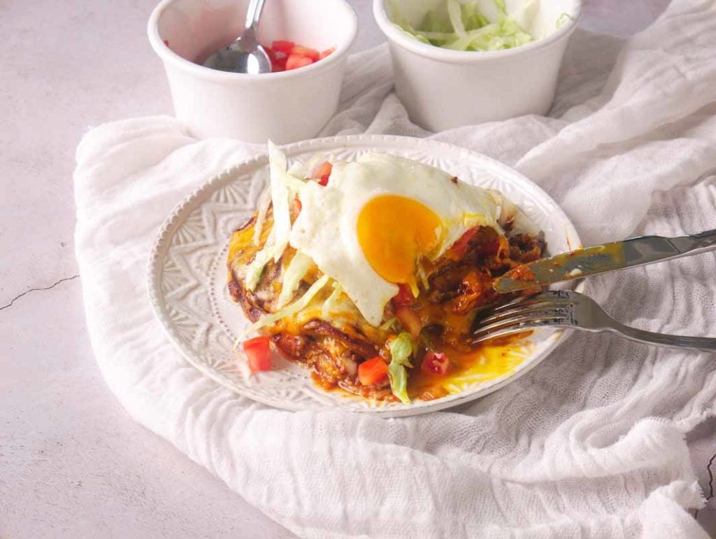 Eating New Mexico Stacked Enchiladas with a knife and fork.