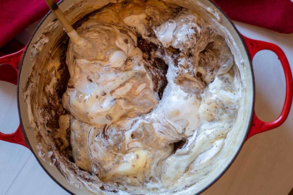 mixing chocolate chips and marshmallow cream into sugar mixture to make fudge.