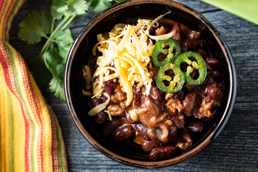 New Mexico style Cowboy Chili Recipe topped with cheese and jalapeno peppers