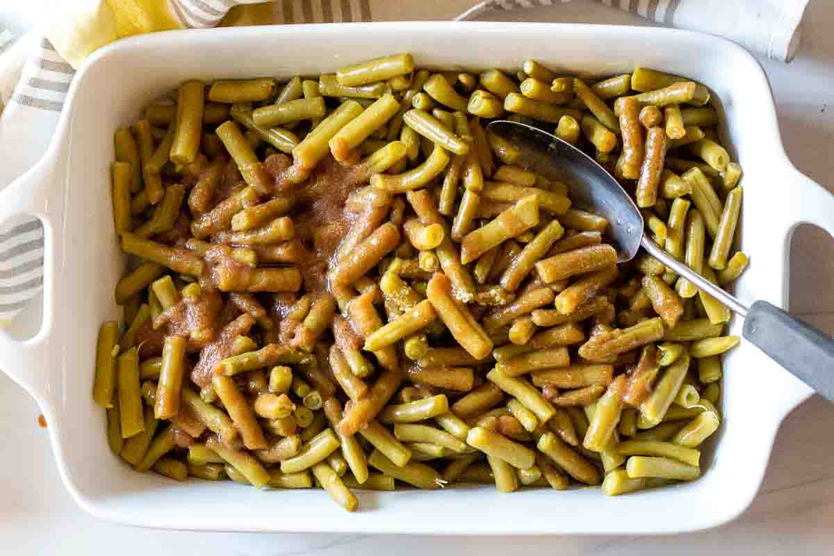 Adding soy sauce mix with green beans in a casserole dish to make green beans with brown sugar.