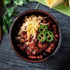 Cowboy chili garnished with grated cheese and jalapeno pepers.