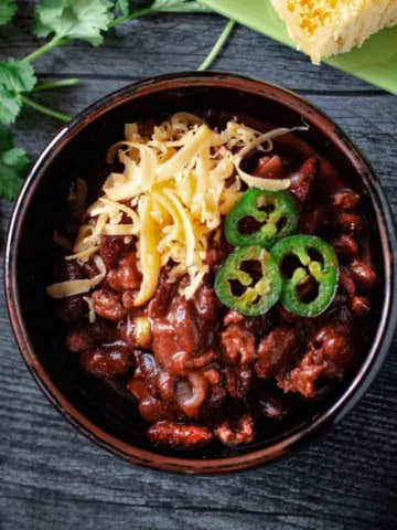 Cowboy chili garnished with grated cheese and jalapeno pepers.