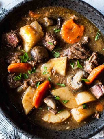 Beef stew with mushrooms served in a skillet.