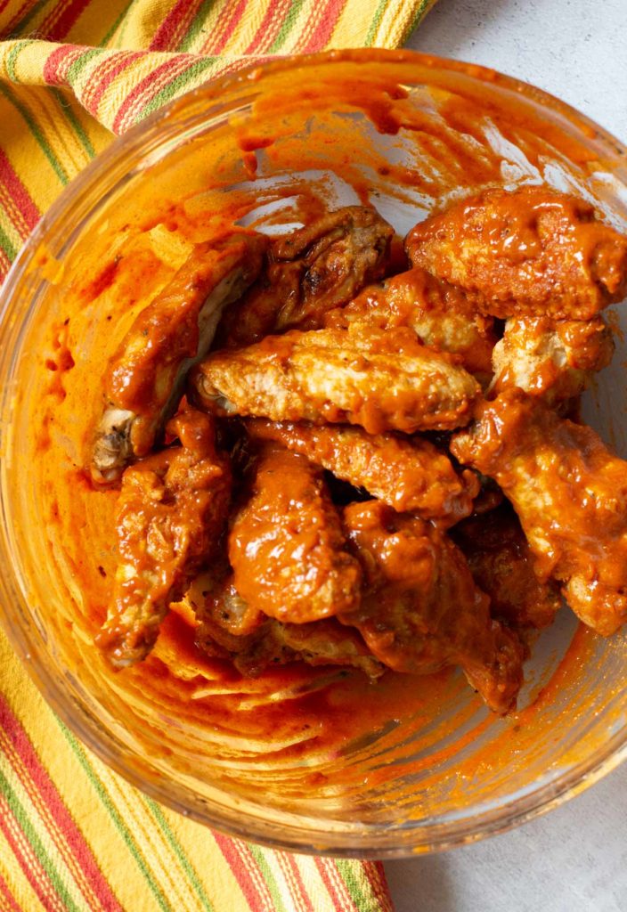 Mixing sauce with baked chicken wings.