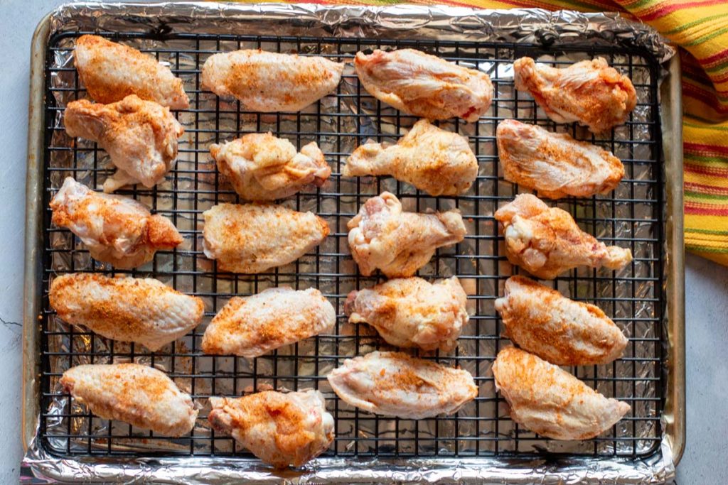 Seasoned chicken wings on a sheet pan fitted with a wire rack.