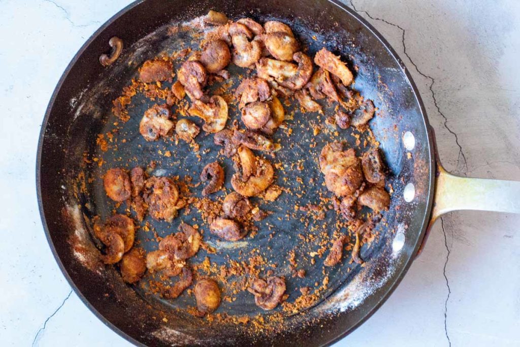 Mixing fried mushrooms with flour and paprika.