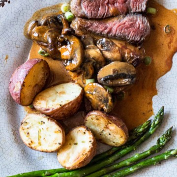 Pan seared picanha beef steak with creamy mushroom sauce, roasted potatoes and asparagus.