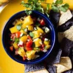 Mango Pico de gallo in a blue Fiesta bowl served with corn chips.