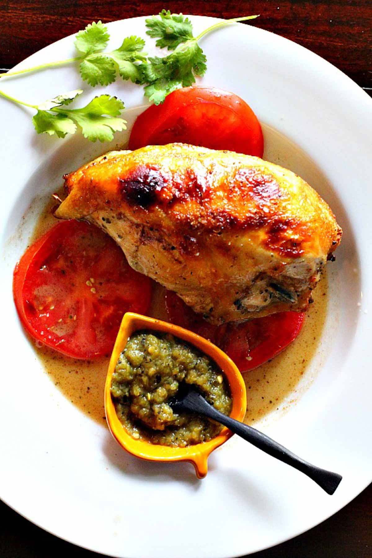 Roasted chicken breast served over fresh tomatoes with salsa verde.