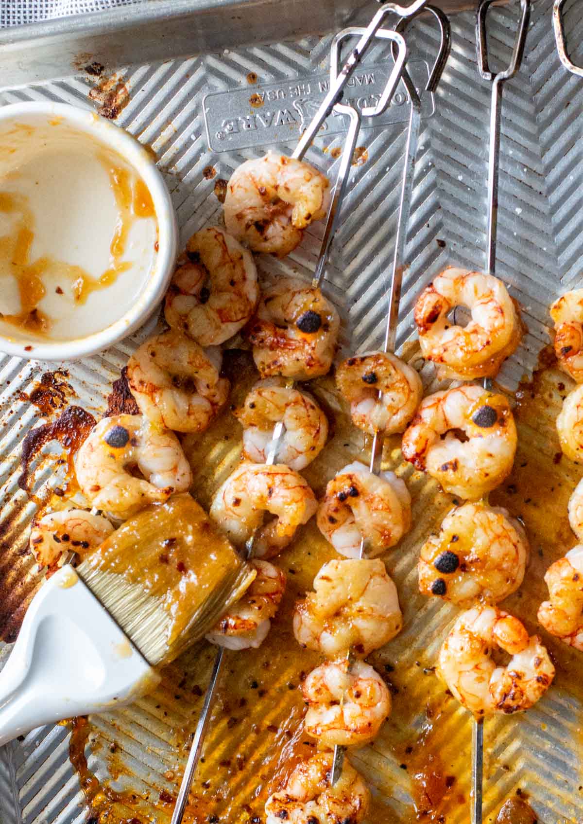 Shrimp skewers on a sheet pan that have been broiled and glazed.