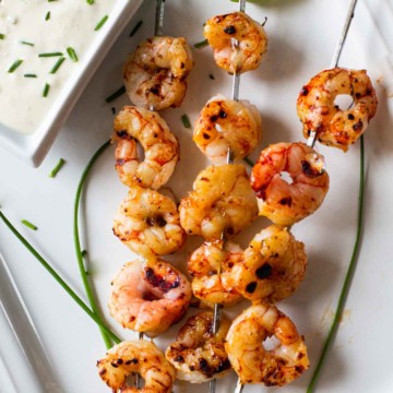 Grilled firecracker shrimp served on a white platter with blue cheese dressing dipping sauce.