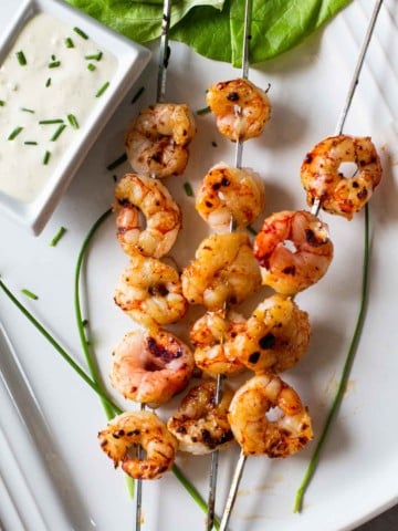 Grilled firecracker shrimp served on a white platter with blue cheese dressing dipping sauce.