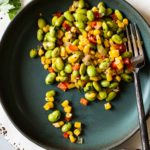 Corn succotash with edamame and red bell pepper on a blue plate.