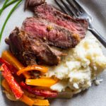 Bison steak recipe served with mashed potatoes and sauteed red and orange bell peppers.
