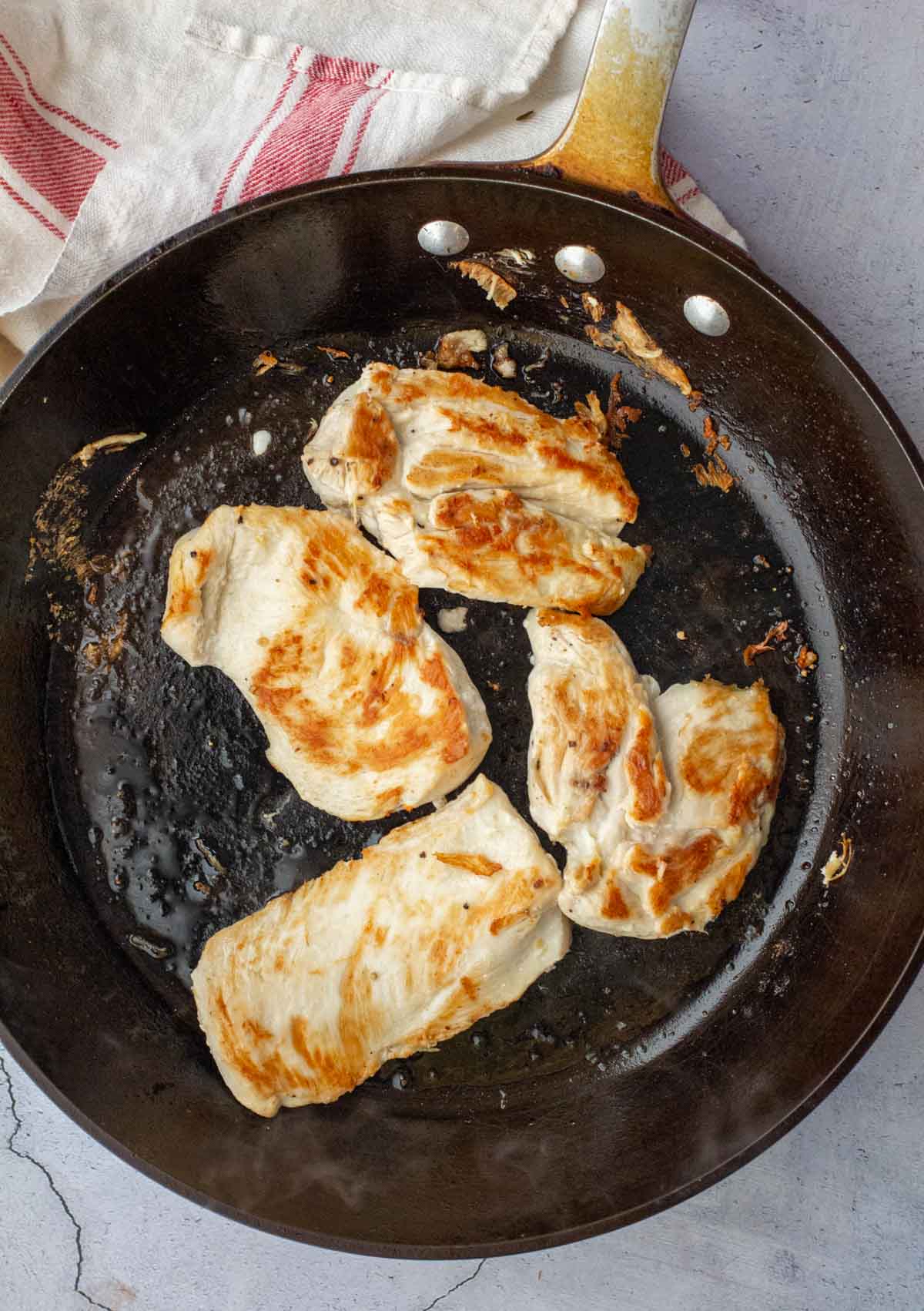 Searing chicken breast cutlets in a heavy skillet.