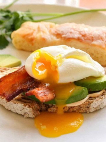 Open faced avocado and egg sandwich with bacon.