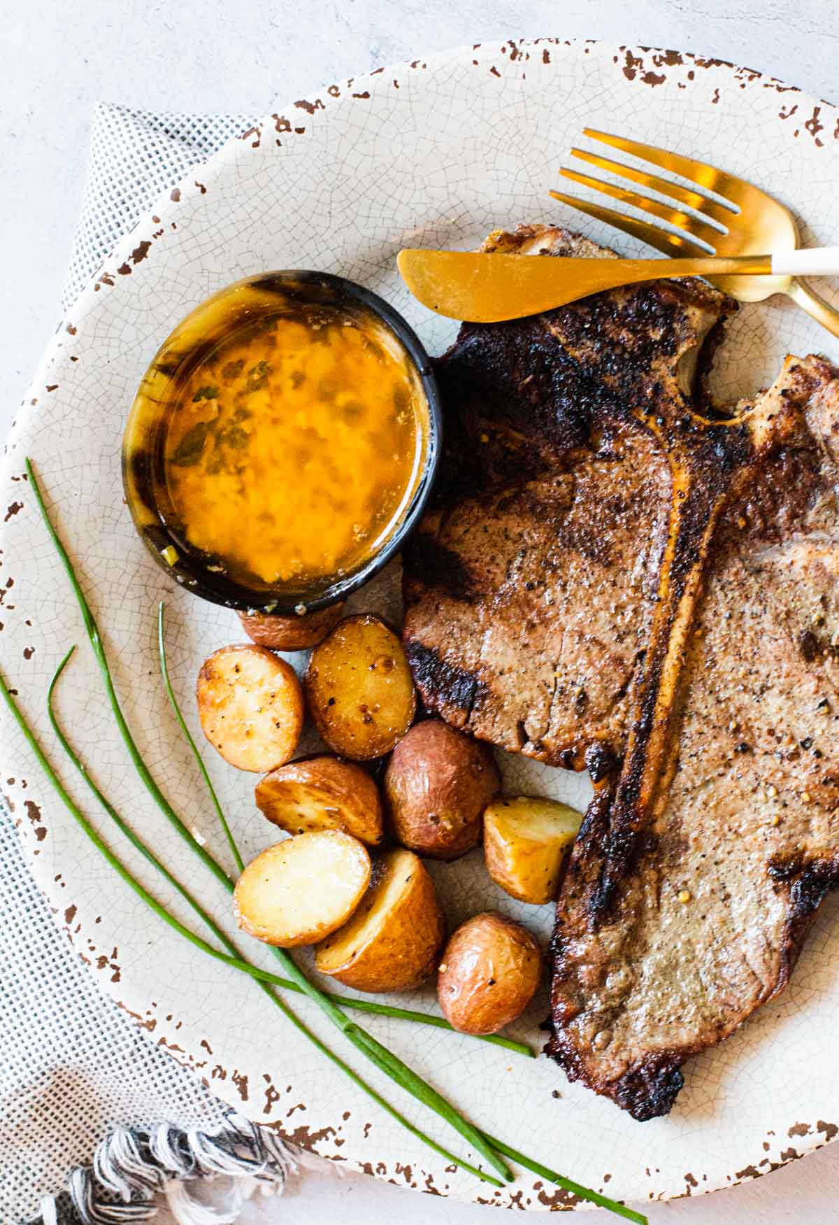 Grilled t-bone steaks served with potatoes and cowboy butter dipping sauce.