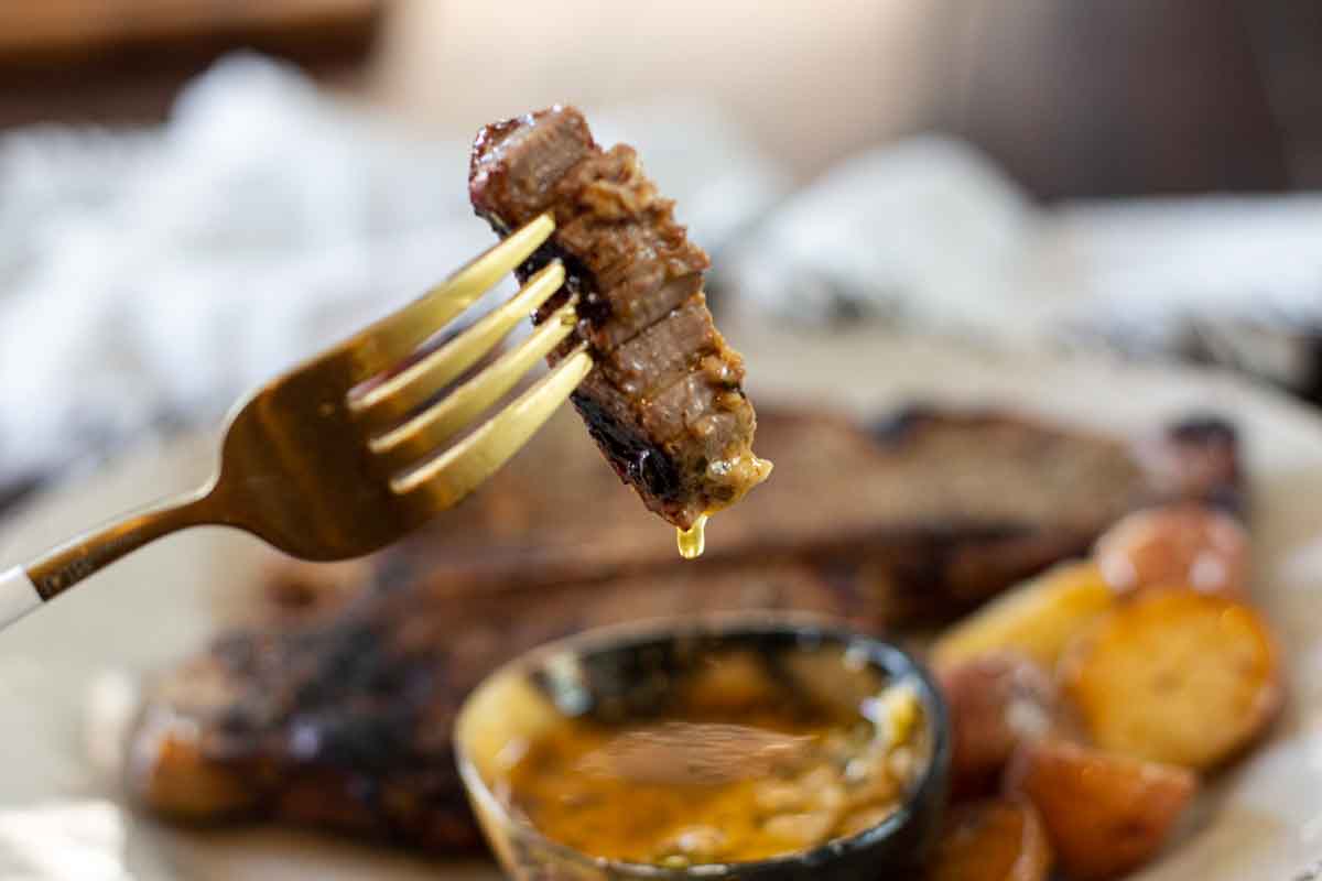 A slice of grilled t-bone steaks dipped in Cowboy Butter.