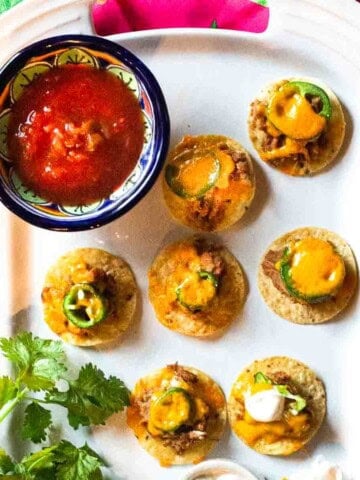 Air fryer nachos on a white Le Creuset platter served with salsa.