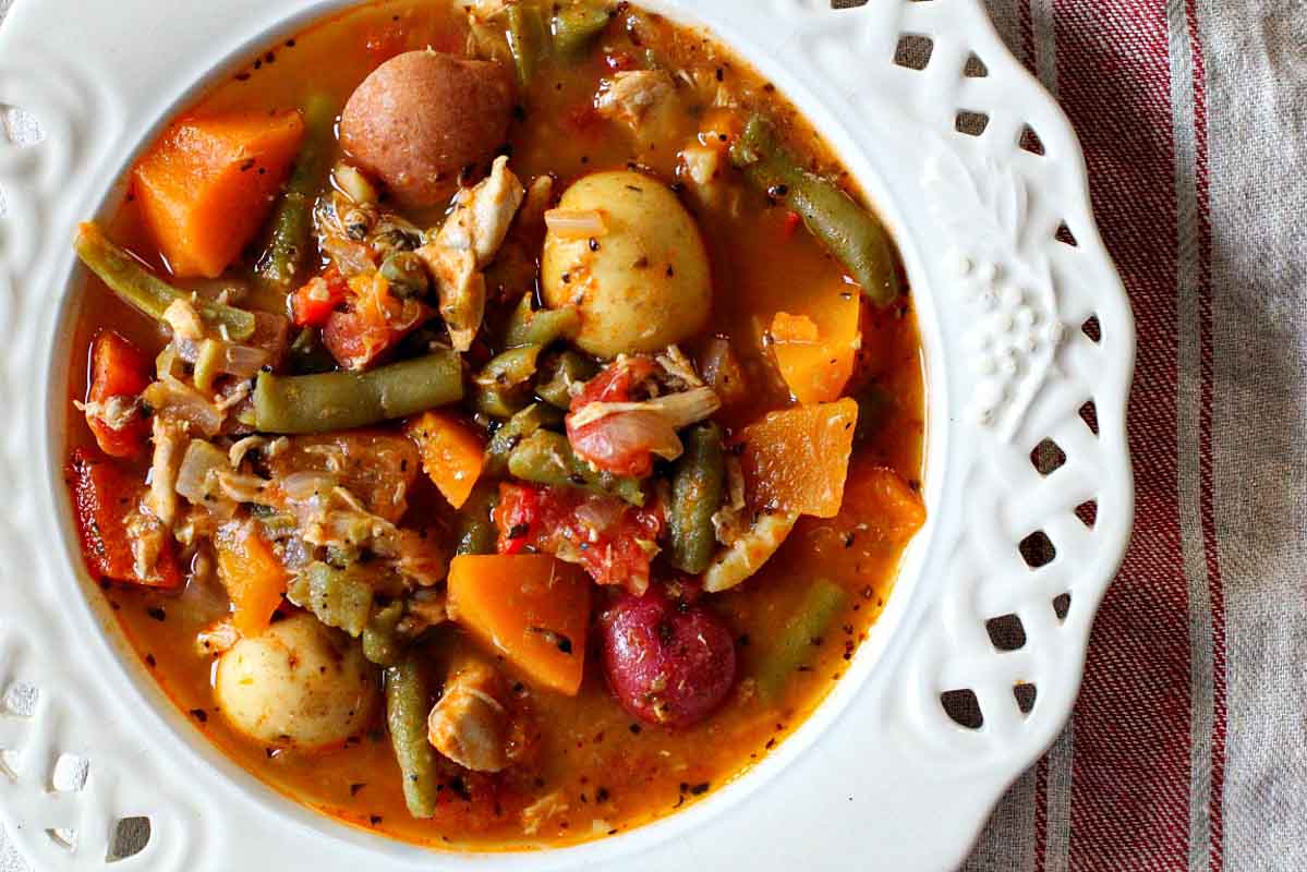 Chicken potato soup with vegetables served in an italian white bowl.