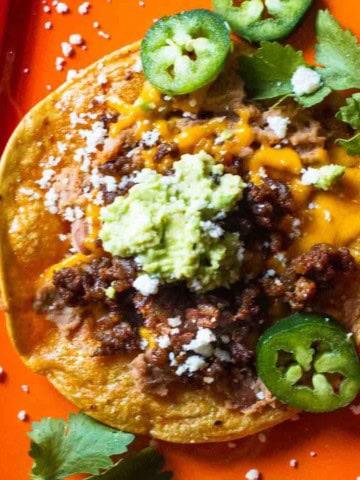 How to make a tostada with chorizo, refried beans and toppings.