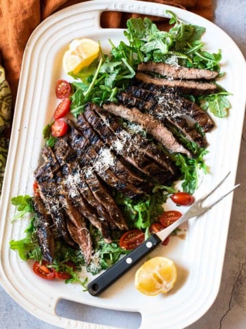 Beef Tagliata served on a bed of arugula and cherry tomatoes.