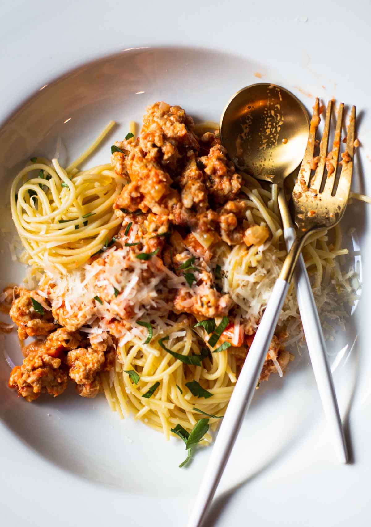 Chicken bolognese served on a pasta plate topped with parmesan cheese.