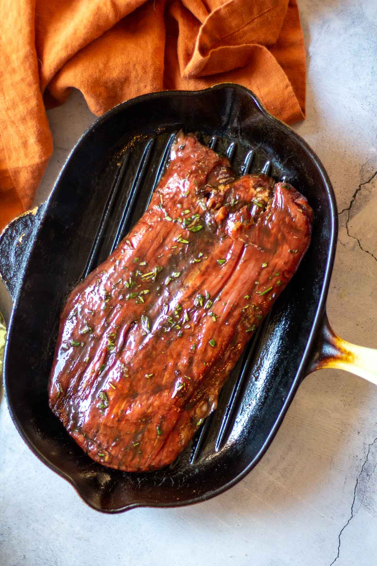 Cooking balsamic marinated flank steak in a grill pan stove top.