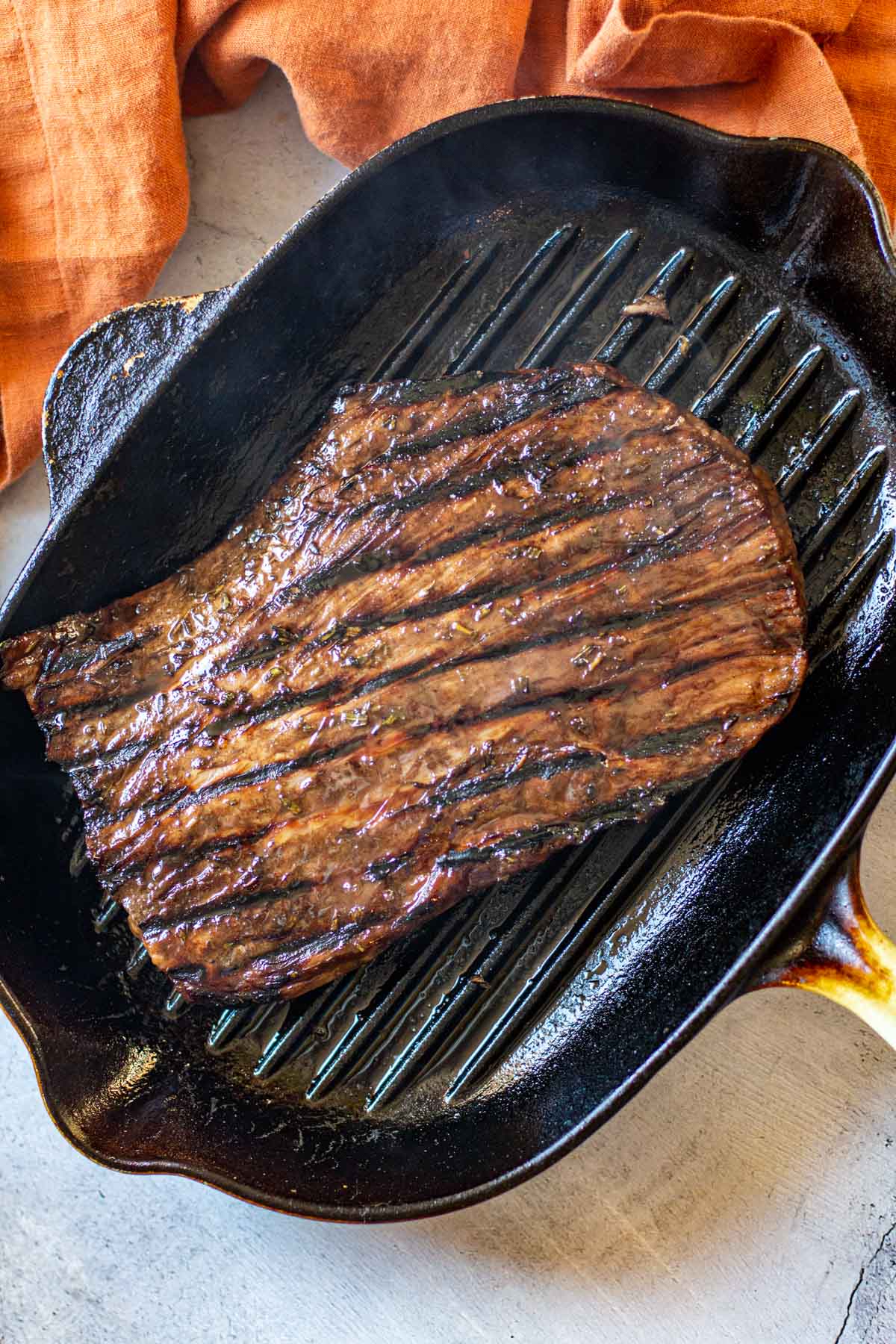 Cooked flank steak in a grill pan stove top.