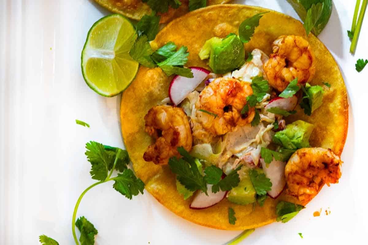 Adding toppings to shrimp tostadas.