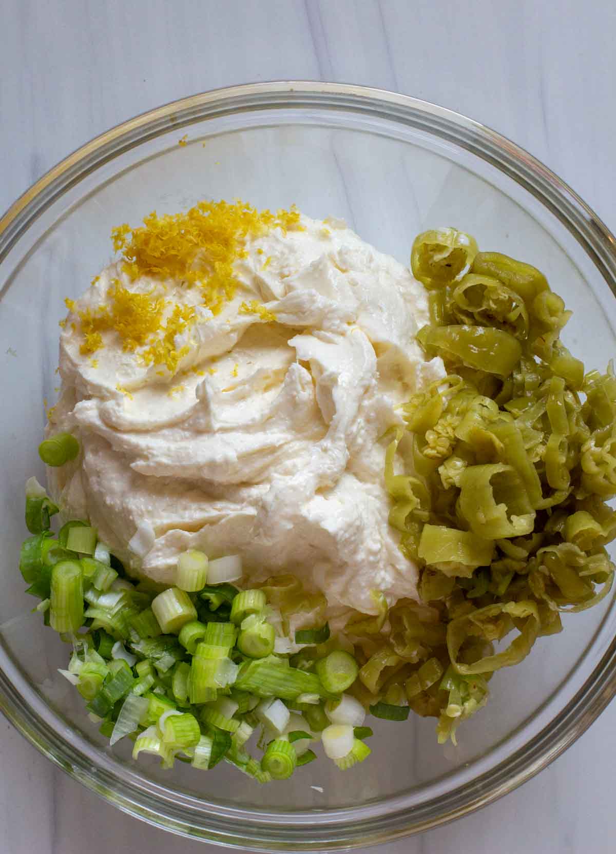 Adding vegetables to cream cheese and feta cheese.