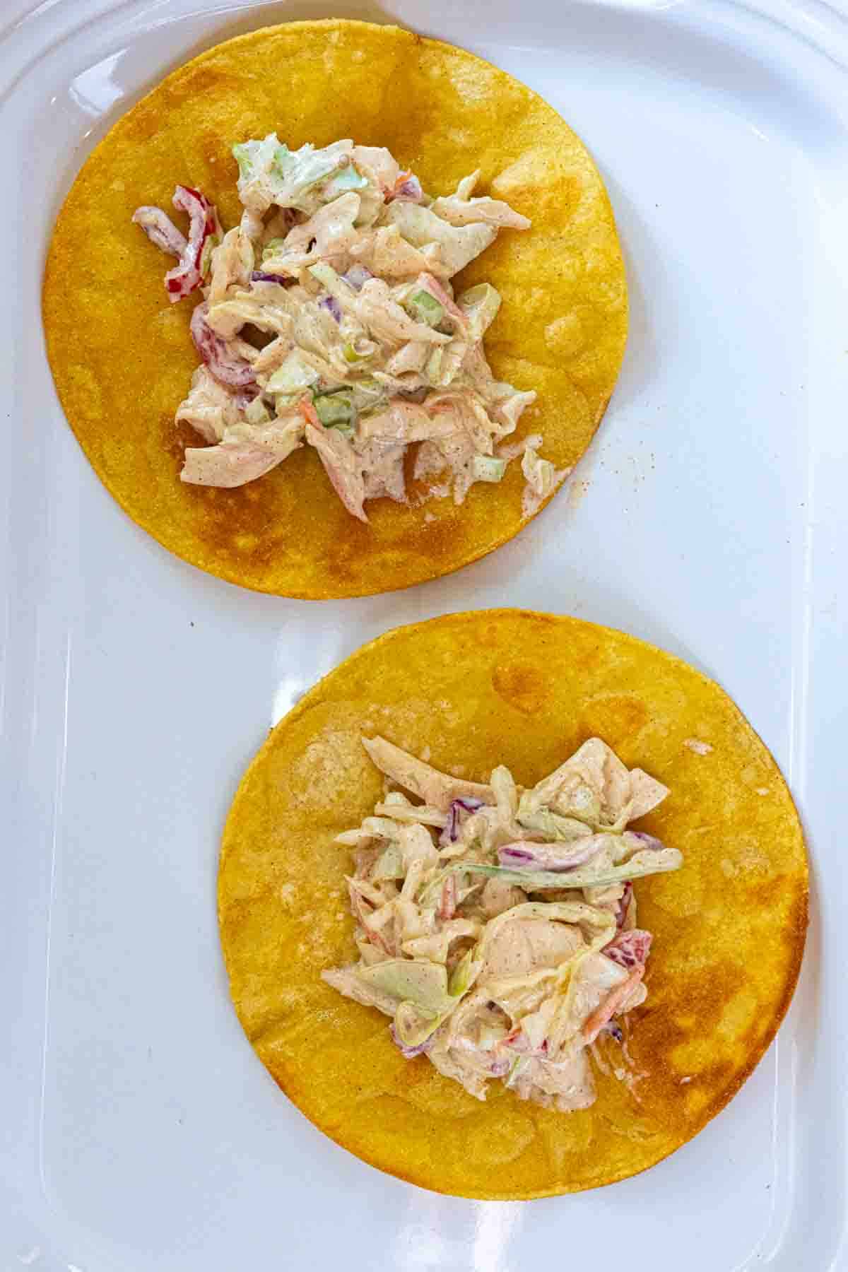 Adding Southwestern Slaw to Tortilla Shells to make Shrimp Tostadas.