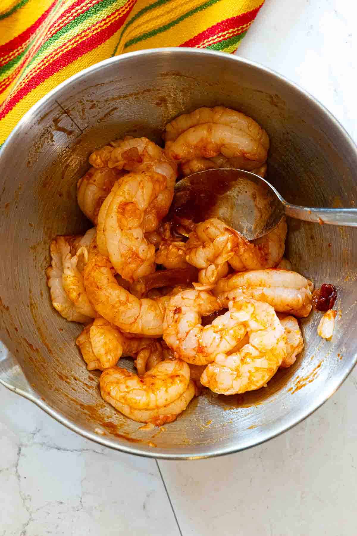 Coating shrimp in adobo sauce to make shrimp tostadas.