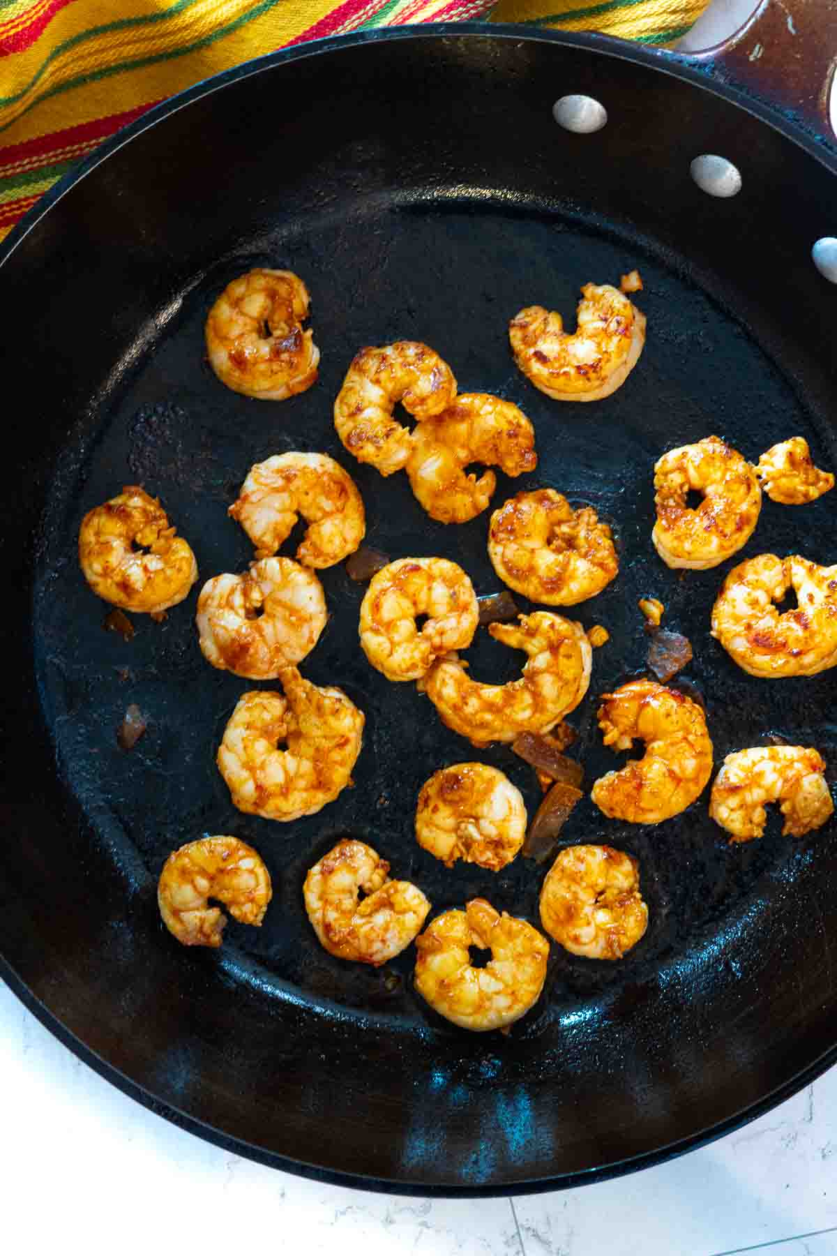 Cooking shrimp in a cast iron pan to make shrimp tostadas.