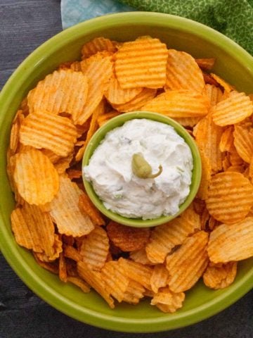 Whipped feta dip with bbq potato chips in a green serving bowl.