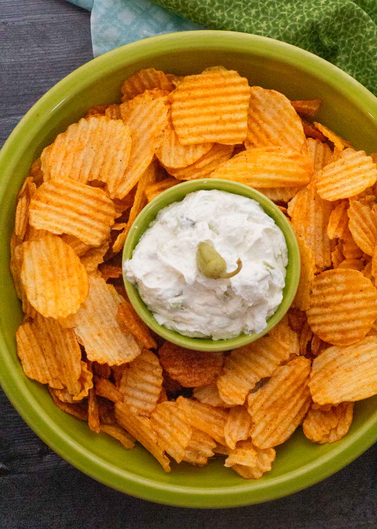 Whipped feta dip with bbq potato chips in a green serving bowl.