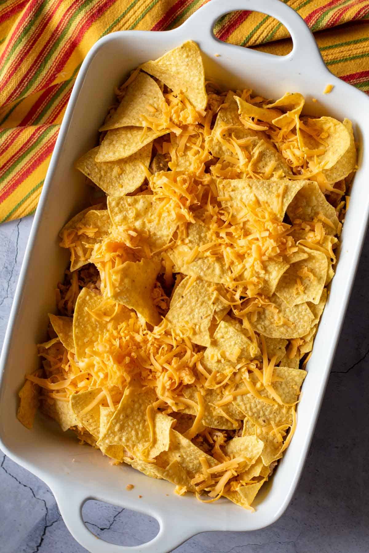 Adding more cheese and chips to chicken taco casserole, step 7.