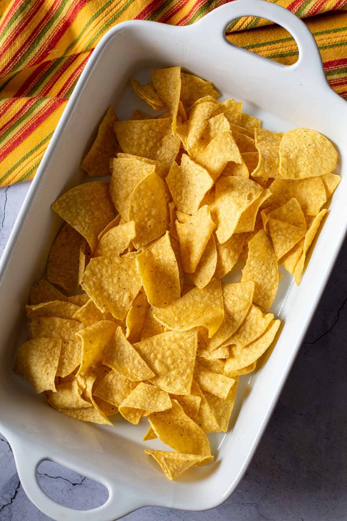 Step 4: Adding corn chips to casserole dish to make Mexican Chicken Casserole.