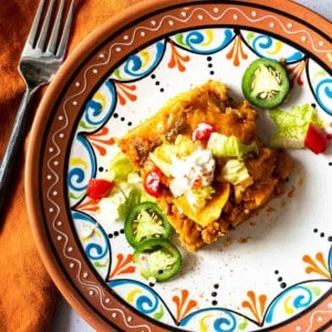 A slice of chicken taco casserole on a Mexican plate.