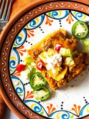A slice of chicken taco casserole on a Mexican plate.