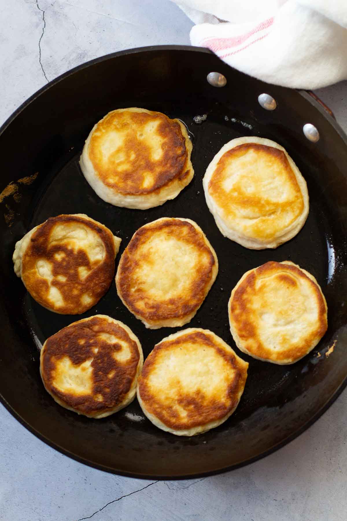 Fried biscuits in a large fry pan.