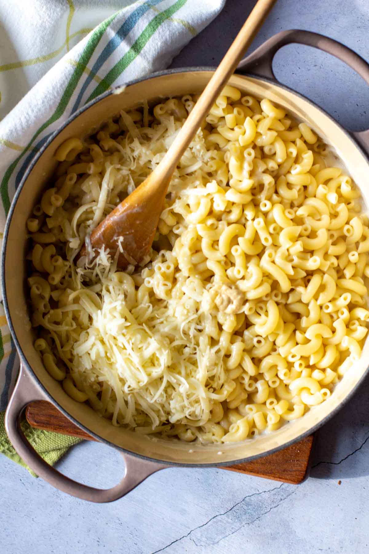 Adding cheese to stove-top macaroni to make white cheddar mac and cheese.
